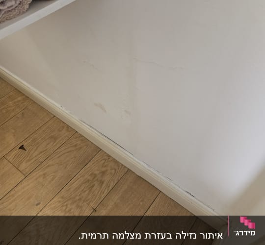 קיר עם סימני רטיבות וסדקים ליד הרצפה